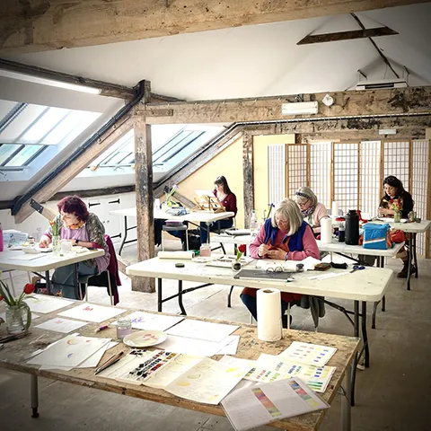 botanical painting workshop students at tables painting in light attic studio
