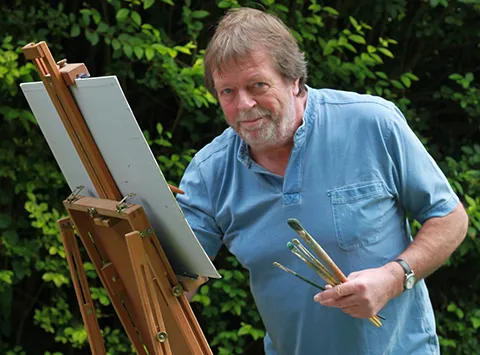 Kevin Scully stood painting at an easel
