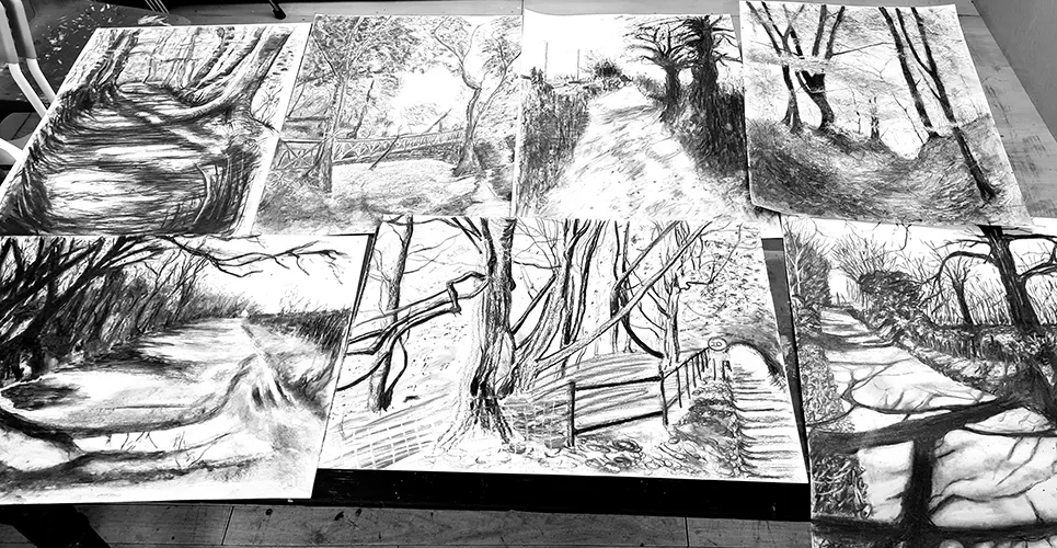 selection of charcoal landscape or tree drawings on table