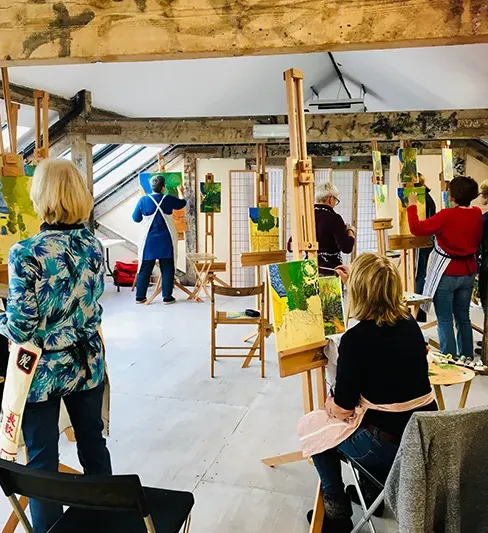 close up of artists painting on easels in large studio space
