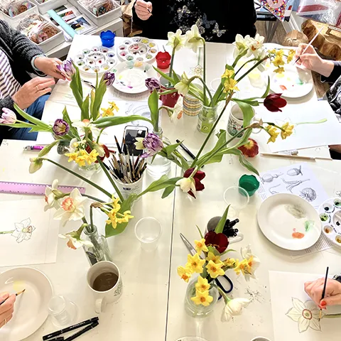 Karen Green watercolour  workshop with spring flowers in vase and students painting around table