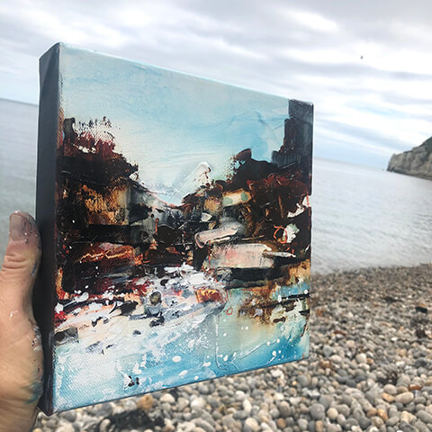 Mel Cormack-Hicks - holding small canvas painting on beach